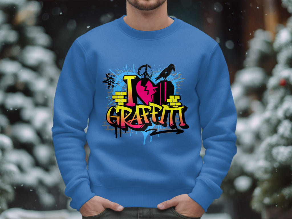 A person dons a blue sweatshirt from Garment Graphics, featuring vibrant street art text I Love Graffiti, while standing in a snowy outdoor scene with snow-covered trees as a stunning backdrop.