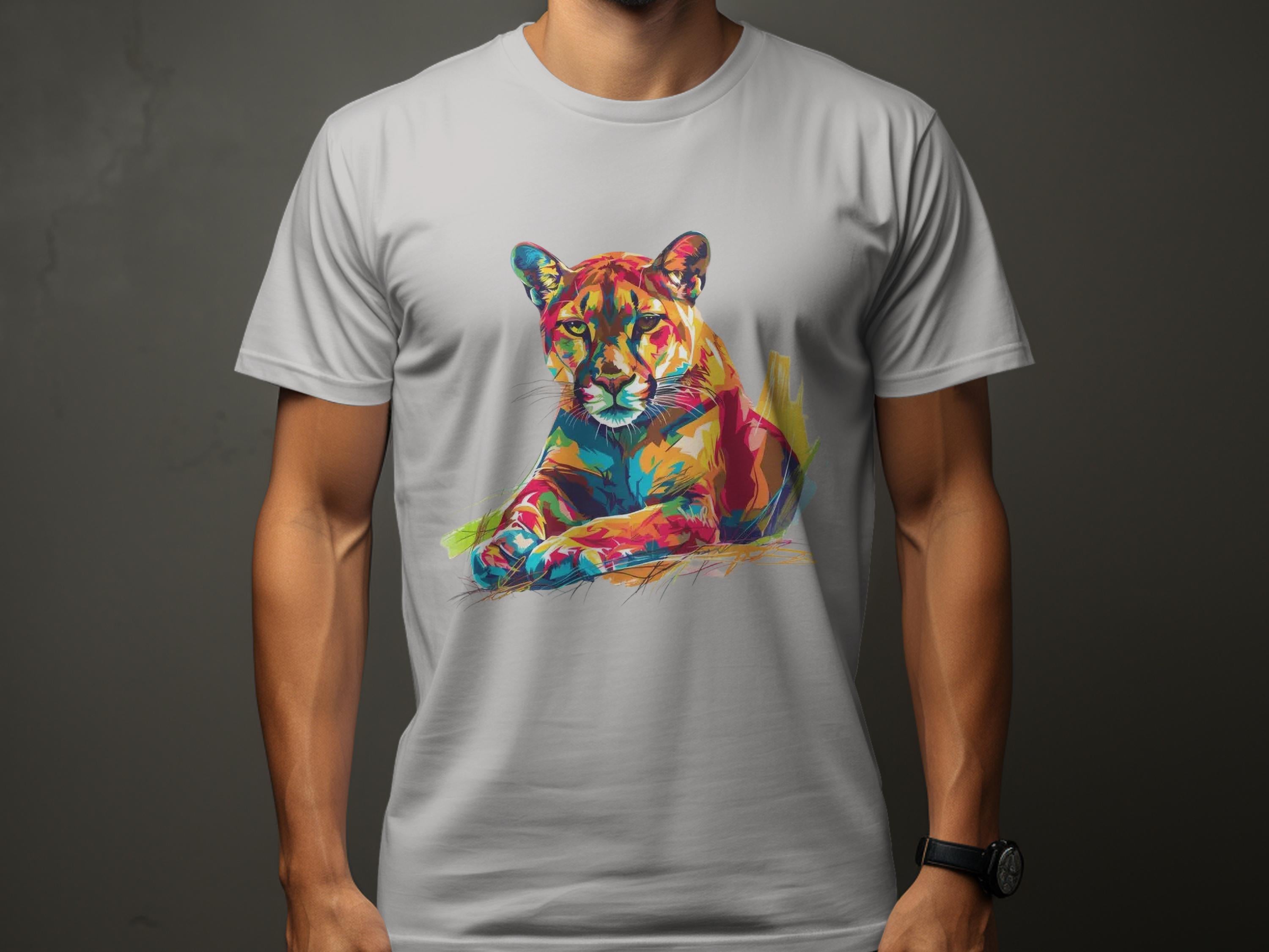 A person wears a Garment Graphics T-shirt featuring vibrant artwork of a roaring cougar in shades of orange, blue, green, and yellow on a dark gray background.