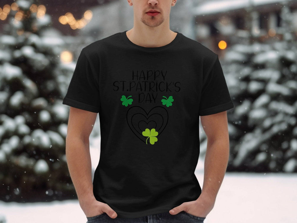 Wearing a Garment Graphics Happy St. Patricks Day black graphic T-shirt with green clovers, a person brings festive flair to snow-covered trees, hands in their jeans, blending holiday cheer with winters beauty.