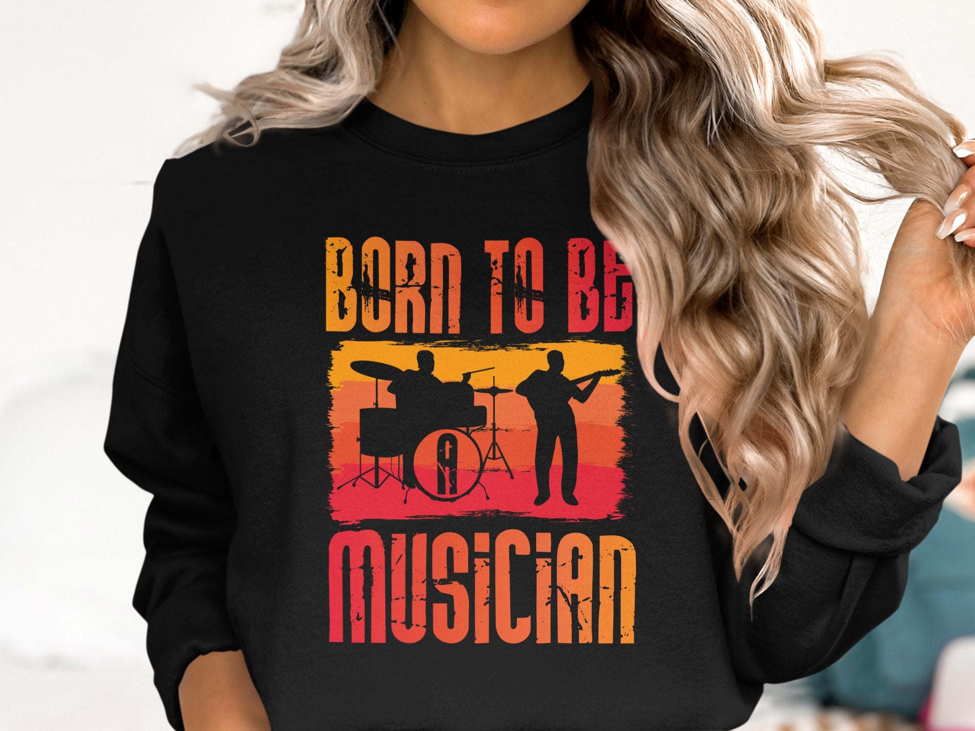 A person with long, wavy blonde hair wears a black unisex-sized Garment Graphics sweatshirt. It features two musician silhouettes and bold Born to Be Musician text, perfect for music lovers.