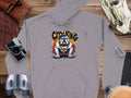 The Garment Graphics gray hoodie, with a classic fit and bulldog design in a spiked collar and harness labeled CITY KING, makes a great casual addition. Its displayed on wood alongside a camera, binoculars, gloves, and leather notebook.