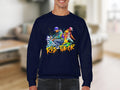 A person is wearing a dark blue Garment Graphics sweatshirt featuring a vibrant design of two figures in colorful street dance attire. Below the artwork, the text Risk Taker Street Dance captures the spirit of fearless competition.