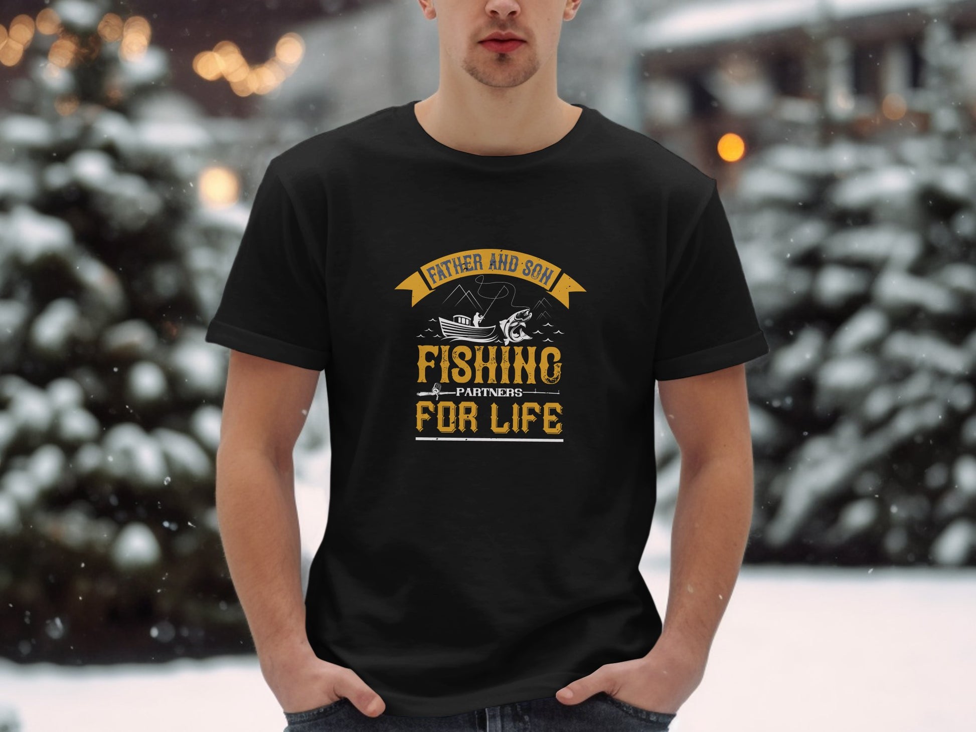 In a snowy setting, someone wears a Garment Graphics black T-shirt with Father and Son Fishing Partners for Life, celebrating family bonding. The shirt features an illustration of two people fishing in a boat, enhanced by snow-covered trees in the background.