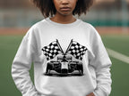 A person sports a Garment Graphics racing car sweatshirt with a black and white illustration of a race car and crossed checkered flags, against a blurred sports field backdrop.