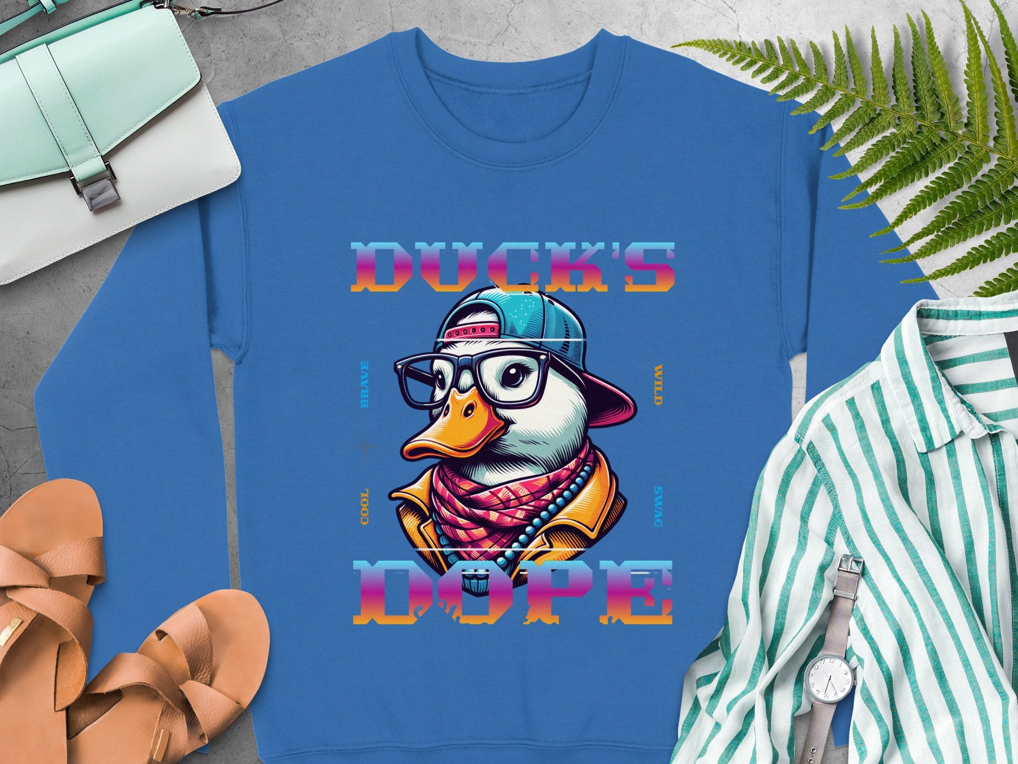 Make a bold fashion statement with Garment Graphics blue sweatshirt featuring a stylish duck cartoon in hip-hop attire and Ducks Dope text. Complete the chic look effortlessly with the included purse, sandals, and striped shirt. .