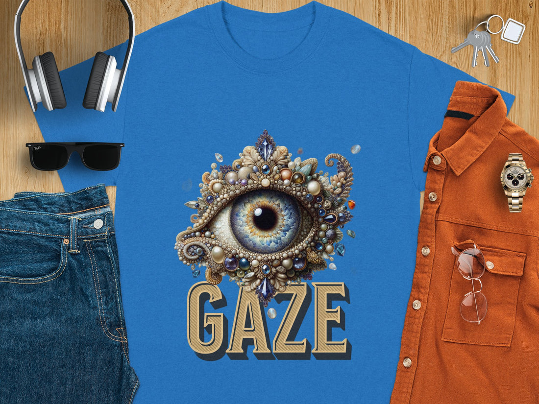 In a grassy, sandy landscape, a person wears a Garment Graphics classic fit white graphic T-shirt featuring an ornate eye design with GAZE boldly displayed.