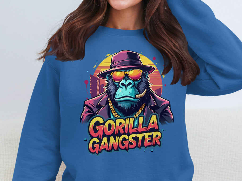 A woman wears a Garment Graphics blue sweatshirt with urban flair, featuring a gorilla dressed as a gangster—complete with hat, sunglasses, chain, and cigar. Bold Gorilla Gangster text is displayed below.
