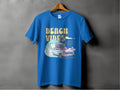 Garment Graphics presents a graphic T-shirt on a hanger featuring a classic car with surfboards, surrounded by waves and palm trees. BEACH VIBES in retro font embodies sun-kissed adventures.