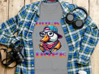 The Garment Graphics gray T-shirt features a colorful duck in a cap and glasses with DUCK DOPE text. Styled with a wooden background, blue plaid shirt, headphones, camera, and white cup—perfect for those embracing bold cool swag. Medium-heavy fabric ensures comfort and durability.