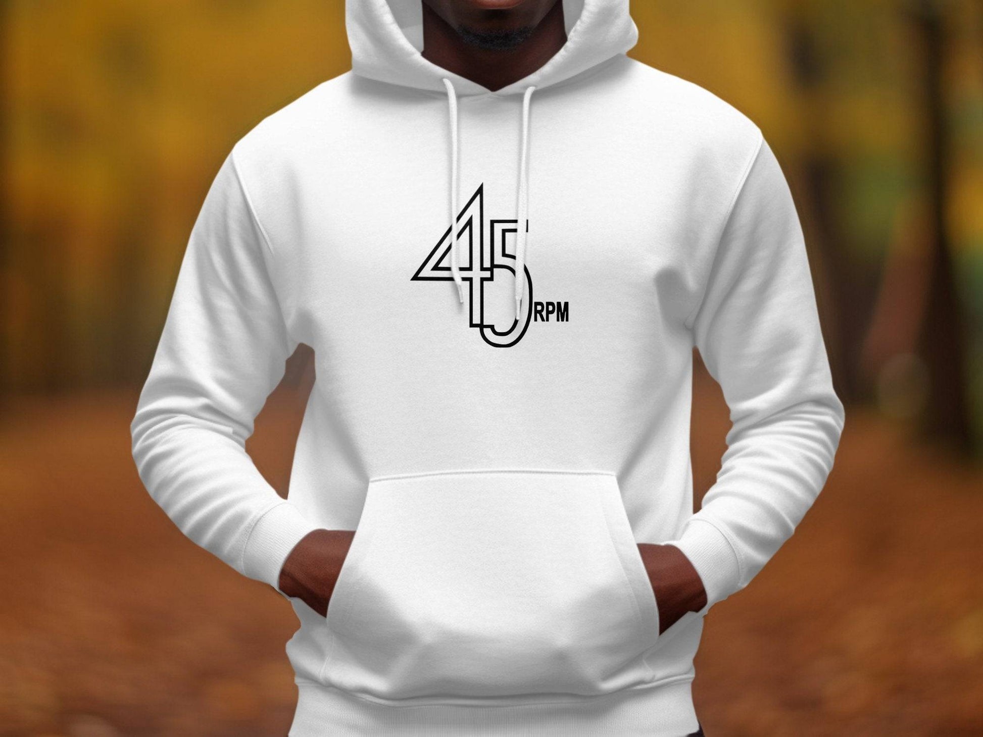 Sporting a Garment Graphics Retro Music Hoodie with 45 RPM on the front, an individual poses against blurred autumn foliage, capturing the essence of vinyl record enthusiasts.