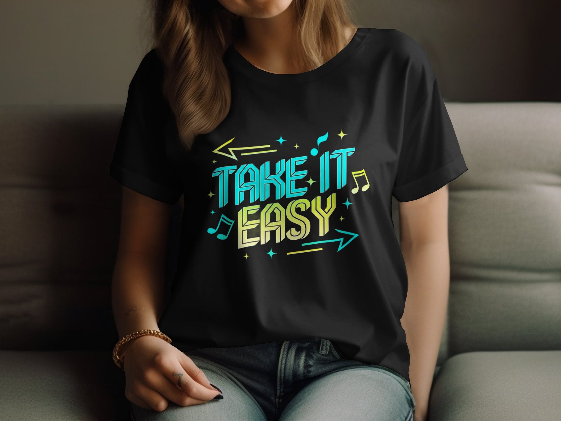 A person wears a black Garment Graphics Take It Easy T-shirt adorned with vibrant blue and yellow musical notes and arrows. The stylish design stands out as they sit on a gray couch, with the image showing them from the neck down.