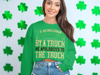 Garment Graphics presents a green unisex sweatshirt with a humorous yellow text: If an Englishman gets run down by a truck he apologizes to the truck. Adorned with green shamrocks, it sits against a light wall, adding charm and humor.