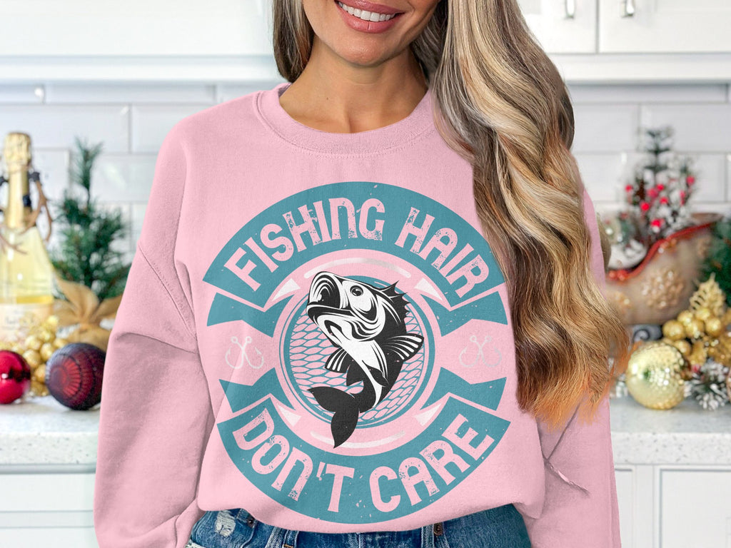 In a festive kitchen with holiday decorations and a white tiled backsplash, a fishing enthusiast wears Garment Graphics light pink sweatshirt, featuring a fish graphic and the phrase Fishing Hair Dont Care.