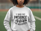 A person outdoors wears a quirky Garment Graphics sweatshirt with I had my patience tested, Im negative text. The unisex sizing suits casual outings, while a softly blurred sports field in the background adds to the relaxed atmosphere.
