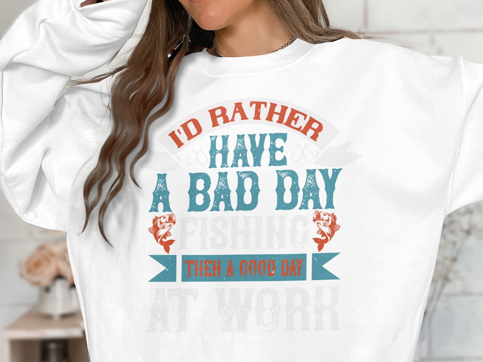 Someone is wearing a Garment Graphics unisex fishing sweatshirt featuring the text Id rather have a bad day fishing than a good day at work in a stylized font, highlighting their preference for angling over office tasks.