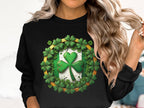 Someone with wavy blonde hair wears a black sweatshirt from Garment Graphics, featuring a prominent green shamrock surrounded by smaller ones, showcasing Irish spirit against a plain white backdrop.