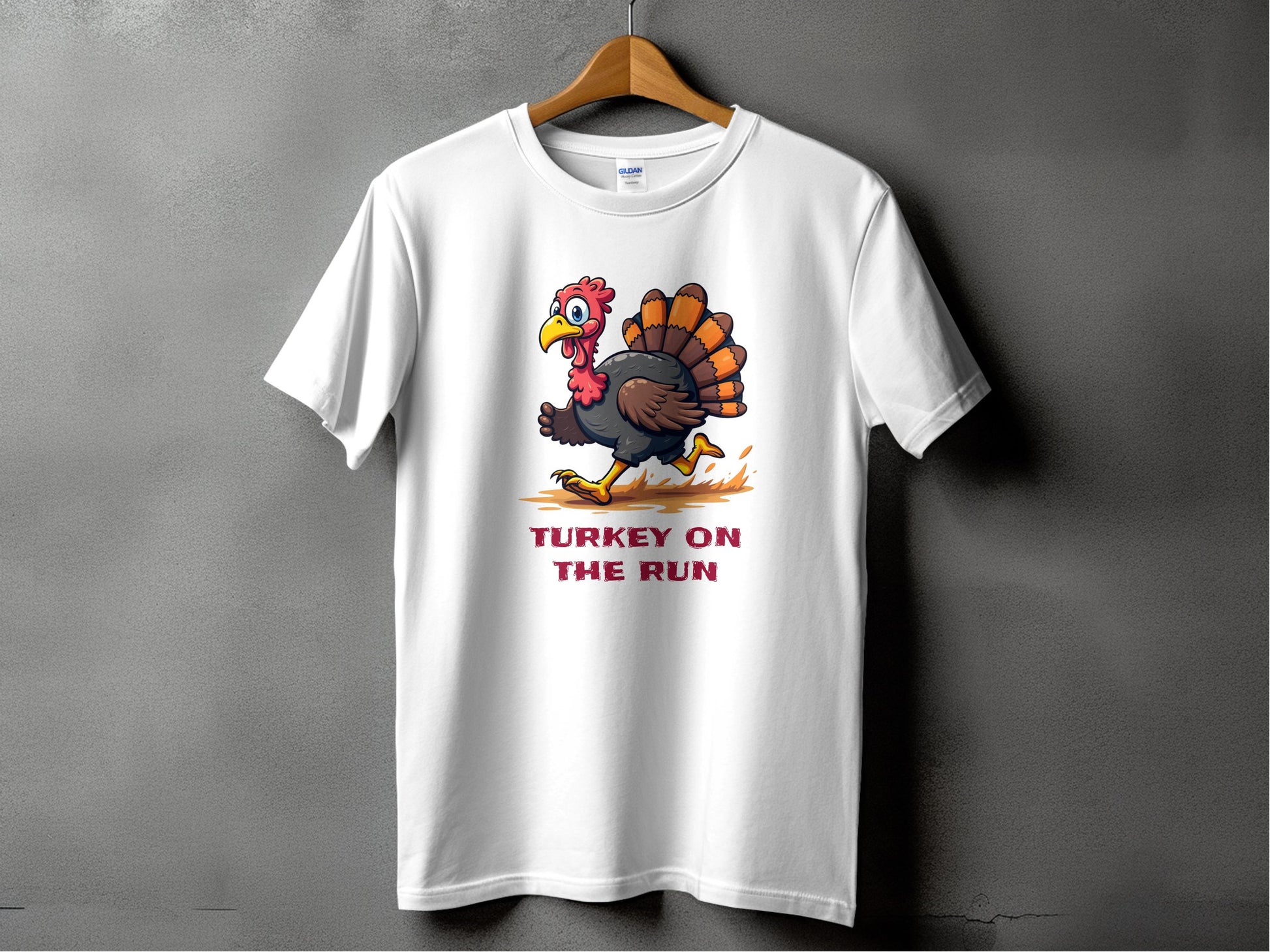This Garment Graphics classic fit white T-shirt features a funny cartoon turkey running with TURKEY ON THE RUN in bold red text below, displayed on a hanger against a gray wall. Perfect for adding humor to your wardrobe.