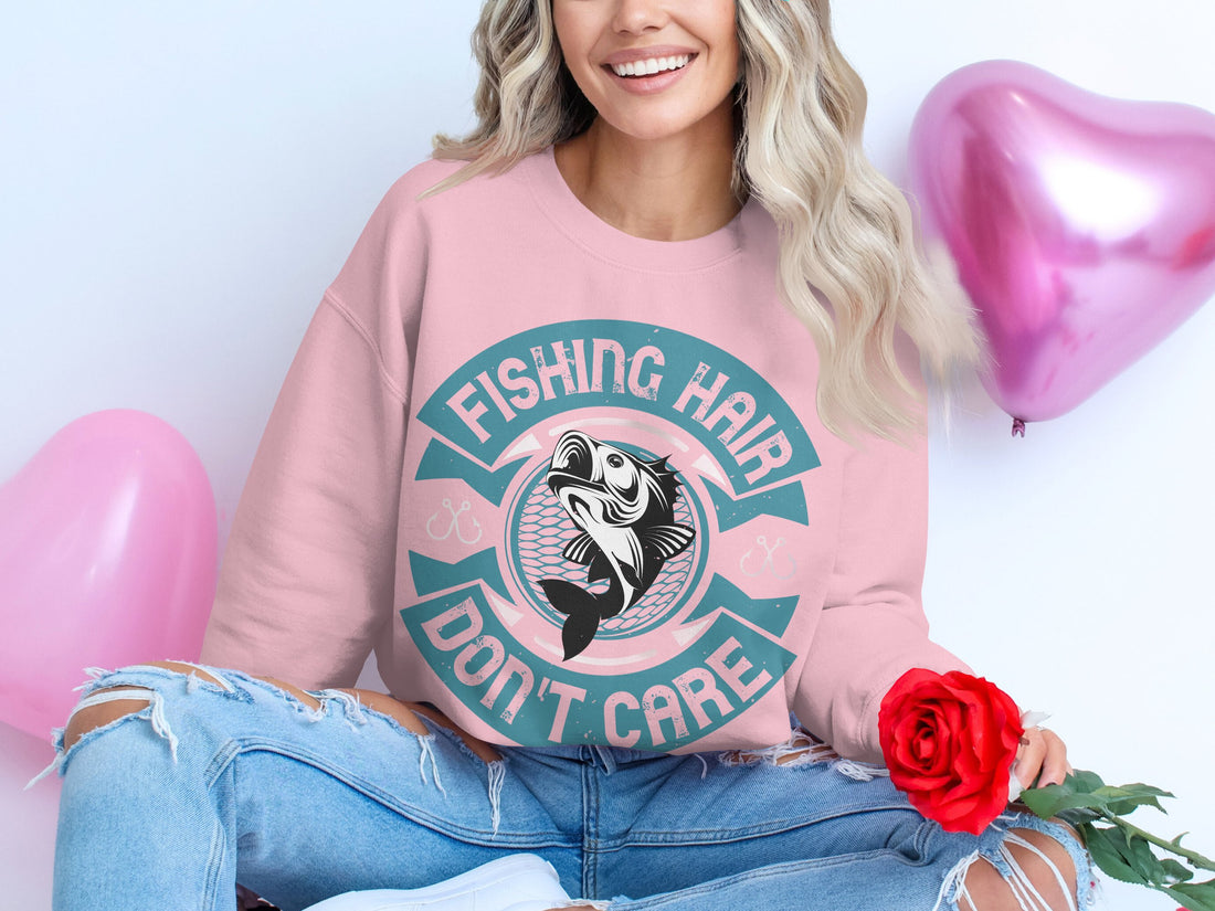 Garment Graphics stylish white sweatshirt with Fishing Hair Dont Care print is perfect for fishing enthusiasts. Presented on a wooden surface, its accompanied by a yellow blazer, pink shoes, makeup brushes, an eyeshadow palette, sunglasses, nail polish, and a blue pouch.