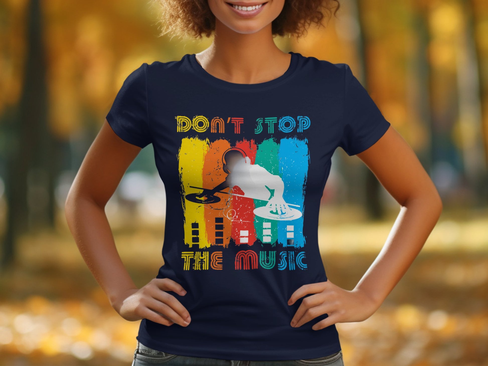 A music enthusiast in a Garment Graphics dark blue DJ graphic tee, showcasing a vibrant DJ spinning records with Dont Stop the Music text. The blurred autumn background with trees and leaves enhances this stylish tees appeal.