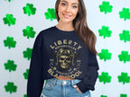 A biker style clad in a black Garment Graphics sweatshirt with a skull, motorcycle graphic, and Liberty Motorcycles Specialist Blackpool 2023, stands among green shamrocks.