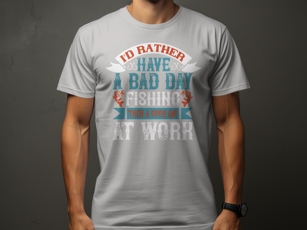 Donning a Garment Graphics light gray fishing T-shirt featuring vibrant artwork and the phrase, Id rather have a bad day fishing than a good day at work, someone stands against a dark backdrop—a great gift for passionate anglers.