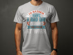 Donning a Garment Graphics light gray fishing T-shirt featuring vibrant artwork and the phrase, Id rather have a bad day fishing than a good day at work, someone stands against a dark backdrop—a great gift for passionate anglers.