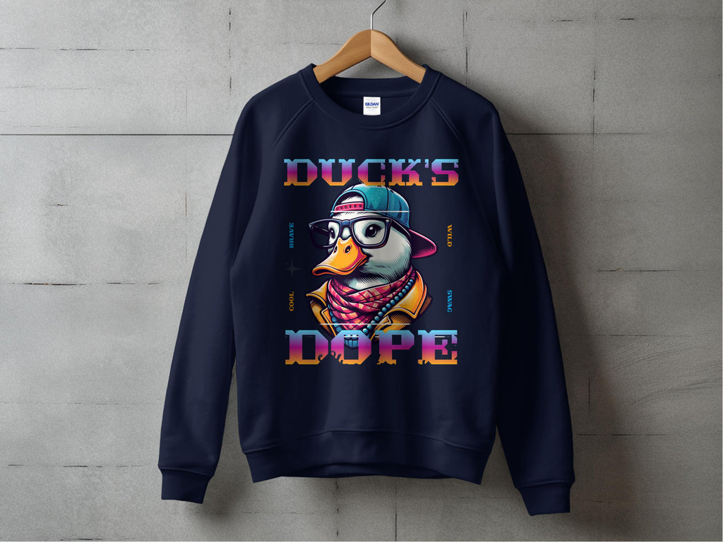 A navy blue Garment Graphics sweatshirt hangs on a wooden hanger against a concrete wall, featuring a cartoon duck with glasses and a hat, and DUCKS DOPE in colorful letters. Made from medium-heavy fabric, it offers unisex sizing for the perfect fit.