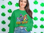 A woman confidently wears a Garment Graphics green sweatshirt featuring the Risk Taker Street Dance 10th Final logo and dynamic dancer graphics. Set against a backdrop of shamrocks on a white wall, she pairs it with blue jeans, capturing her street dance passion perfectly.