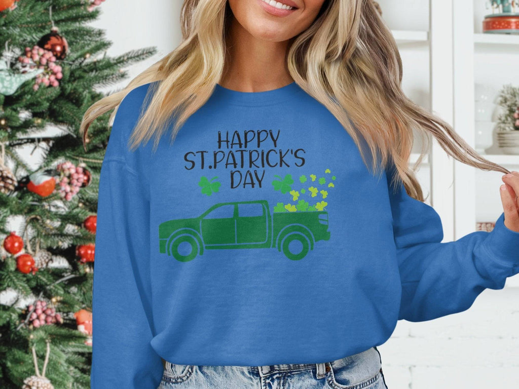 A person wears a festive Garment Graphics sweatshirt featuring a green truck and shamrocks with Happy St. Patricks Day. A subtly twinkling decorated Christmas tree stands in the background.