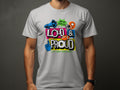 A person wearing a Garment Graphics white t-shirt with colorful graffiti-style text, Loud & Proud, featuring a megaphone, star, and foam finger. Ideal for football sports enthusiasts to showcase passion, it also reads Hey Ho Lets Go! Lets make some noise!.