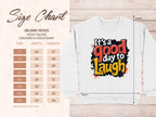 A sizing chart for the Gildan 18000 heavy blend crewneck sweatshirt, displaying unisex sizes S to 5XL with respective width and length, is on the left. On the right, theres a white Garment Graphics Its a Good Day to Laugh Graphic Art Sweatshirt.