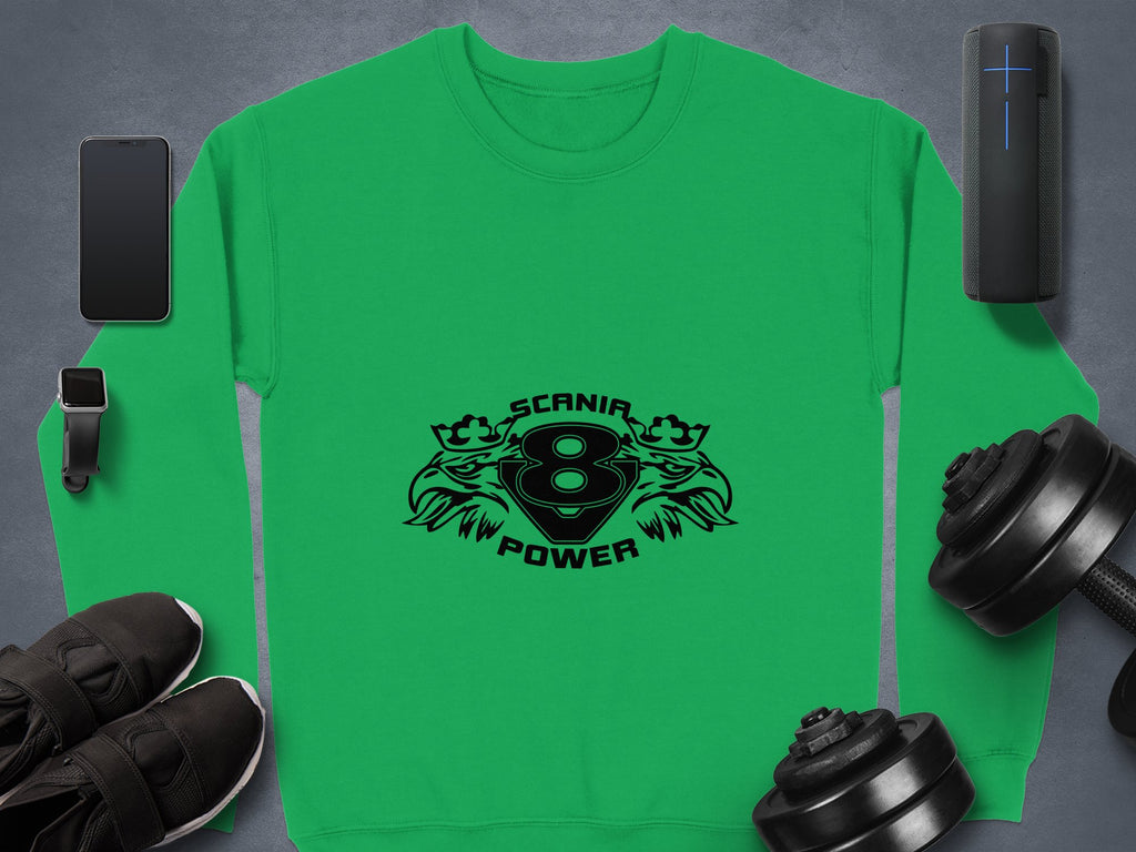 A trendy green sweatshirt from Garment Graphics displays a Scania Power V8 logo with number 8 and flames. Its arranged on a gray surface, paired with a smartphone, smartwatch, sneakers, portable speaker, and dumbbells.
