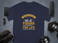 Garment Graphics navy blue t-shirt features Father and Son Fishing Partners for Life with a fish, boat, and waves. Displayed on gray, its surrounded by a smartphone, smartwatch, shoes, wireless speaker, and weights—ideal for celebrating family bonding.