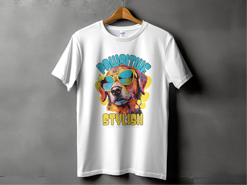 Garment Graphics white dog t-shirt on a hanger showcases a vibrant graphic of a dog with sunglasses, reading Chillin Like A Canine Villain. Against a gray backdrop, this shirt exudes paw-sitive style.