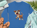 The Garment Graphics blue sweatshirt with a happy animated dog design is ideal for dog lovers. Its displayed on a gray surface surrounded by brown shoes, a green striped shirt, a white watch, a blue purse, and fern leaves.