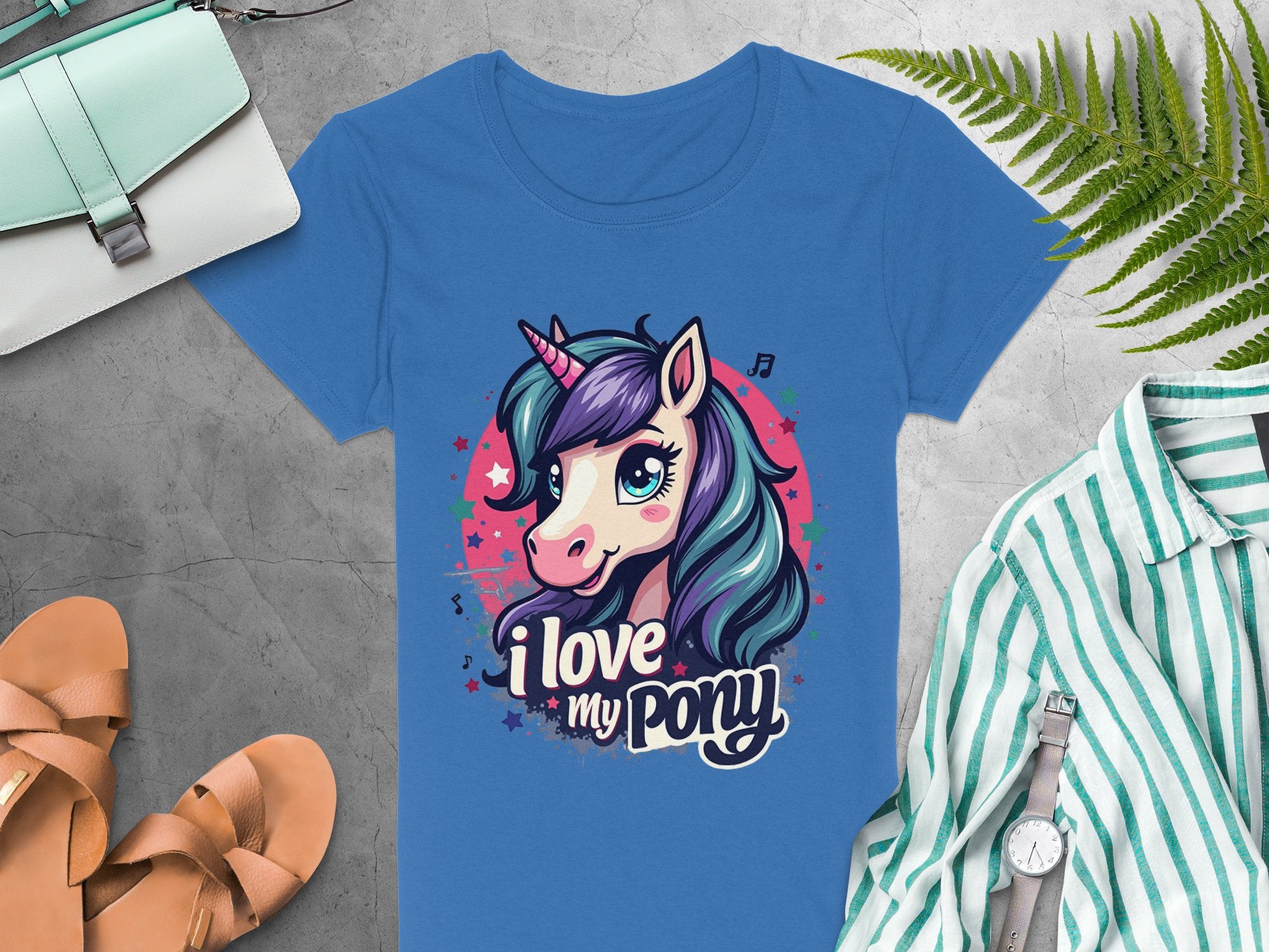 Unicorn lovers will adore this vibrant I Love My Pony T-shirt by Garment Graphics, featuring a colorful unicorn graphic. Styled with chic accessories like sandals, a silver watch, a purse, and a green-striped shirt on gray with a natural touch from the fern leaf.