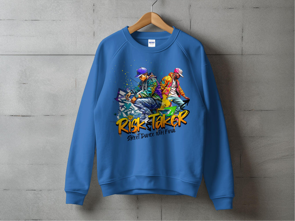 Against a concrete wall, a blue sweatshirt by Garment Graphics features two vibrant illustrated dancers and the bold text RISK TAKER Street Dance with Pride, embodying the street dance finals vibe.