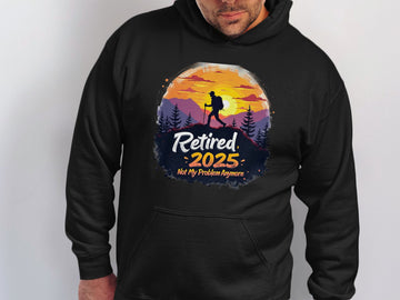 Someone is wearing a Garment Graphics black hoodie that features a vivid sunset mountain scene with a hiker, alongside the bold text: Retired 2025 Not My Problem Anymore.