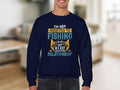 A person in a navy blue, unisex Garment Graphics sweatshirt showcases the text: Im not addicted to fishing. We are just in a very committed relationship, set against a blurred interior backdrop.