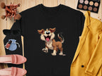 Garment Graphics black sweatshirt with a happy dog illustration sits beside yellow jacket, makeup brushes, eyeshadow palette, pink loafers, and blue pouch on wood—ideal for dog lovers.