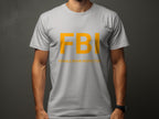 Against a dark background, this person wears a Garment Graphics gray T-shirt featuring bold yellow FBI letters. Underneath, the humorous text reads Female Boob Inspector, offering a truly funny design for fans of witty T-shirts.
