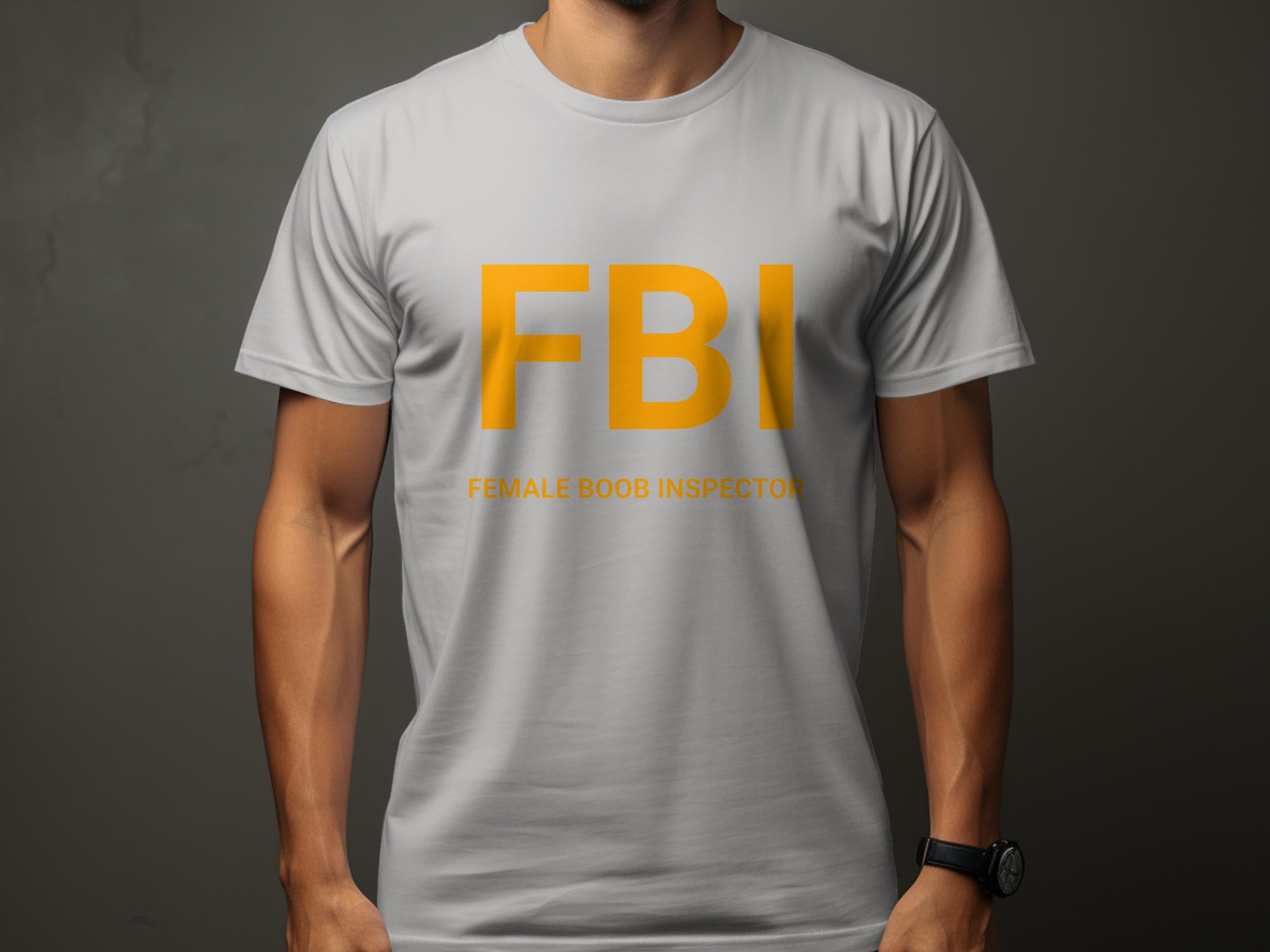 Against a dark background, this person wears a Garment Graphics gray T-shirt featuring bold yellow FBI letters. Underneath, the humorous text reads Female Boob Inspector, offering a truly funny design for fans of witty T-shirts.