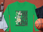 Versatile unisex sizing enhances this Garment Graphics green sweatshirt with a cartoon alligator holding a basketball. See You Later Alligator is written boldly on it, and its set against an orange background with a basketball, black shorts, water bottle, and white towel.