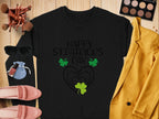 A Garment Graphics festive sweatshirt featuring Happy St. Patricks Day and a clover design sits on wood alongside a yellow jacket, pink loafers, blue pouch, makeup brushes, sunglasses, a compact, and nail polish.