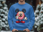Standing outside in the snow, a person is wrapped in a playful Garment Graphics sweatshirt featuring a cute cartoon donut character. With mouse ears, pie eyes, sprinkle-covered face, white gloves, and red shoes, they add charm as blurred trees form the background.
