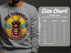Someone wears a gray Garment Graphics sweatshirt with a bee graphic and the text Bee Yourself, Everyone Else Is Taken. This Summer Edition is unisex and follows the Gildan 18000 size chart, available in sizes S to 5XL.