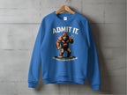 The image shows a Garment Graphics blue sweatshirt on a hanger against a gray wall, featuring a Bigfoot graphic with ADMIT IT and Life would be boring without me. This unisex casual wear item humorously enhances any wardrobe.