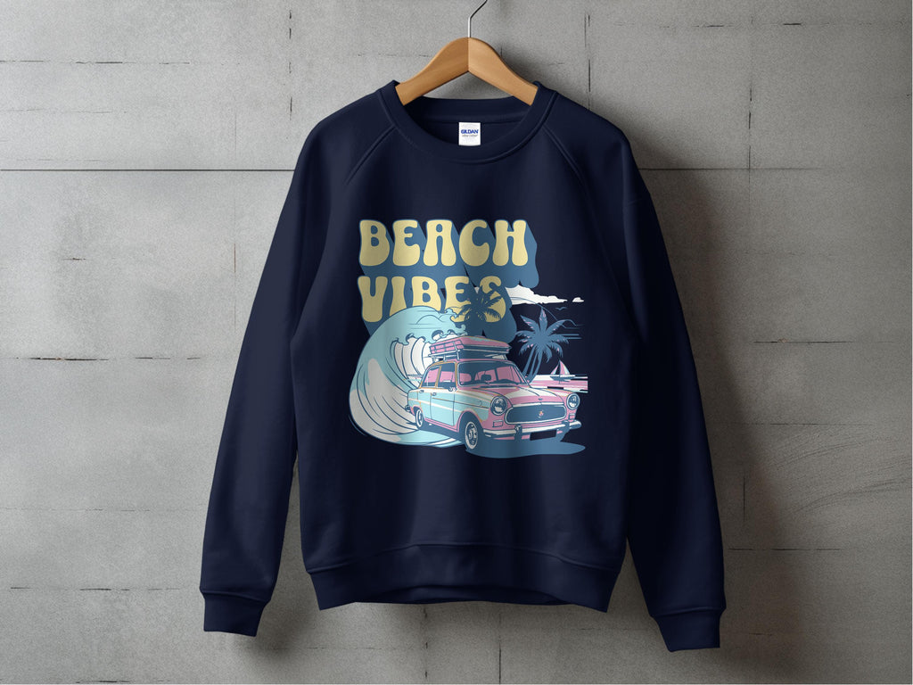 A navy Garment Graphics sweatshirt hangs on a wooden hanger, featuring a vintage car graphic with surfboards, ocean waves, and palm trees, along with Beach Vibes in stylized text. This unisex piece is perfect for lovers of classic graphic sweatshirts.