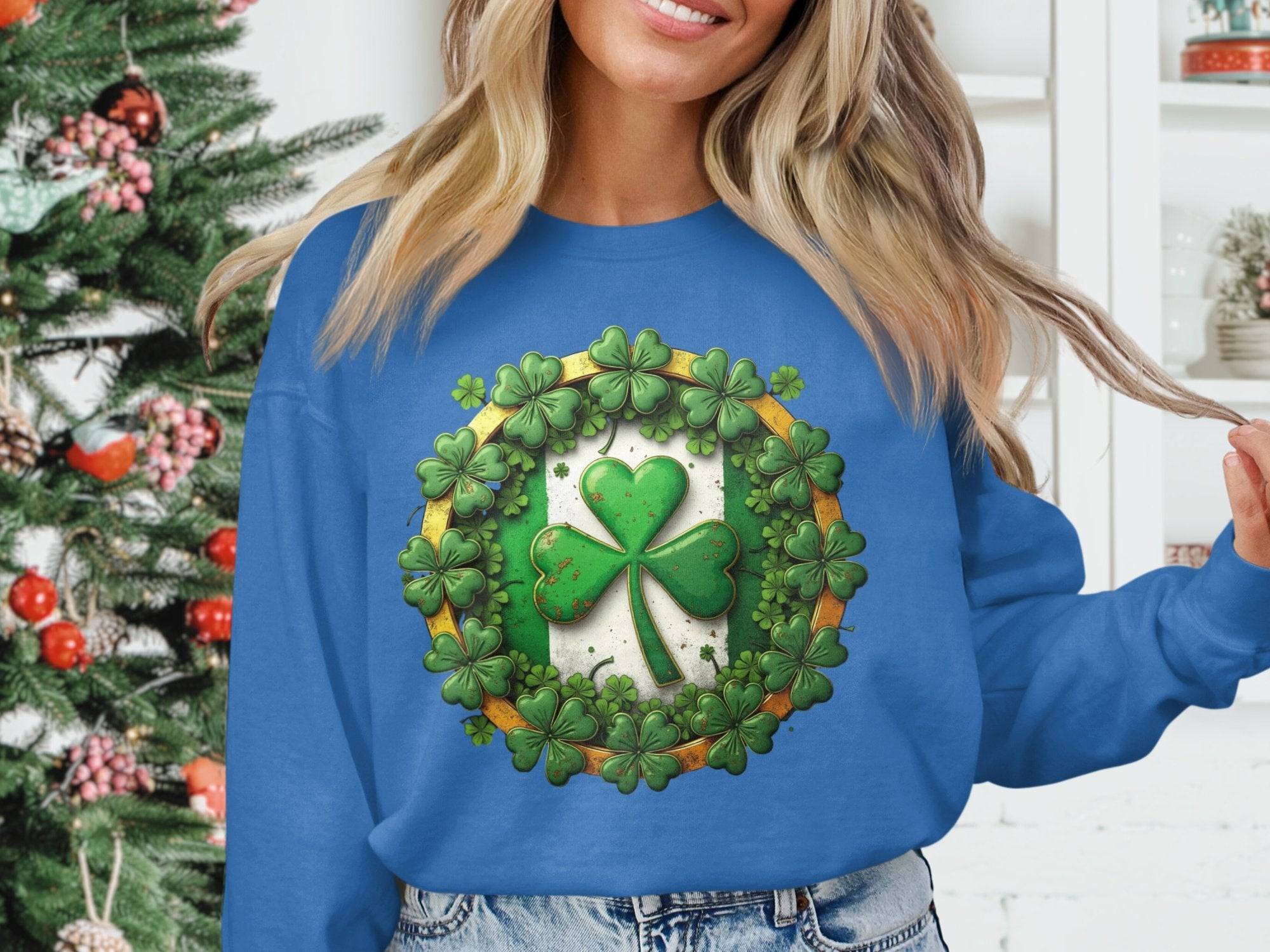 Sporting a Garment Graphics blue sweatshirt adorned with a large shamrock and smaller ones, an individual channels Irish spirit in front of a Christmas tree, holding a section of their long blonde hair.