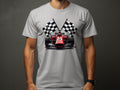 A person is wearing a Garment Graphics gray motorsport T-shirt with a red racing car graphic and two crossed checkered flags on the front against a plain dark gray background.